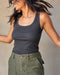 A woman wearing a gray ribbed tank top and green shorts.