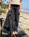 Person holding a jacket on a wooden bench by the beach